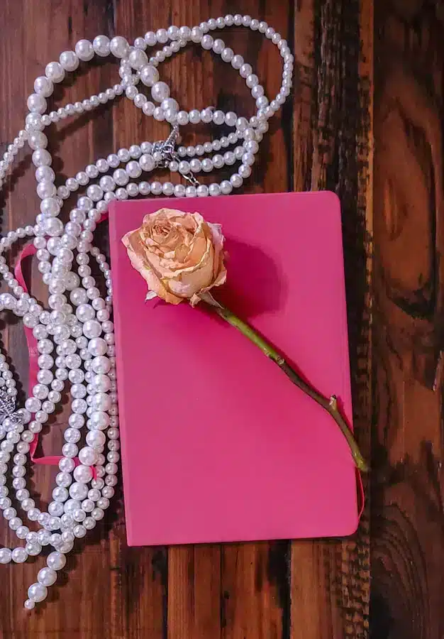 Journaling, the Ultimate Guide On How to do it for Your Personal Growth 1 pink journal with a pink rose over it and a string of white pearl- journaling