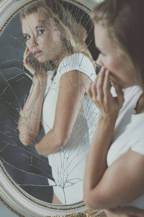 How to Set Personal Boundaries and Say No for Improved Mental Health 1 young woman looking at herself in a broken mirror