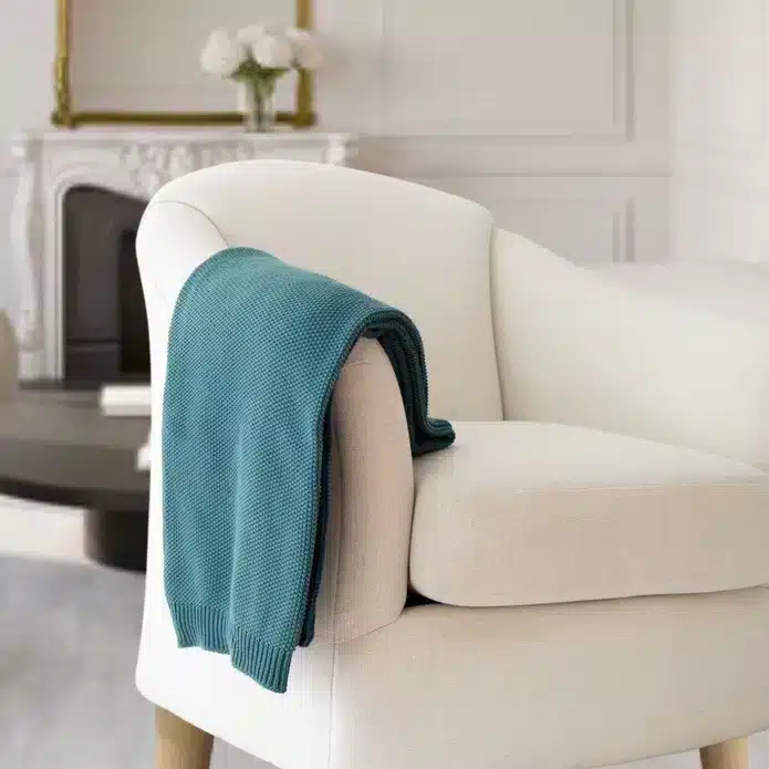 Teal Cotton Seed stitch Knit Throw draped on cream couch