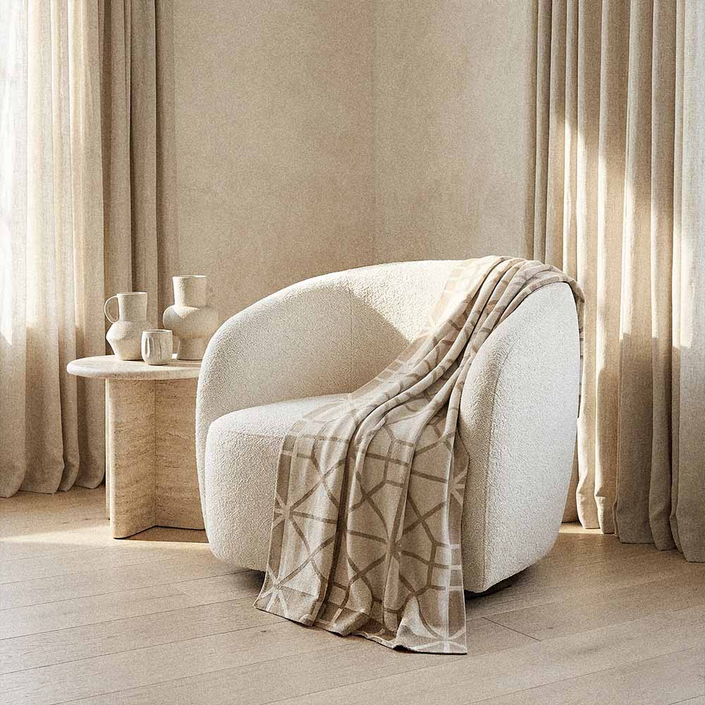 Simone lightweight cotton blanket | Lightweight Geometric Knit 2 ream cotton throw blanket draped on cream upholstered armchair with warm minimalist living room styling