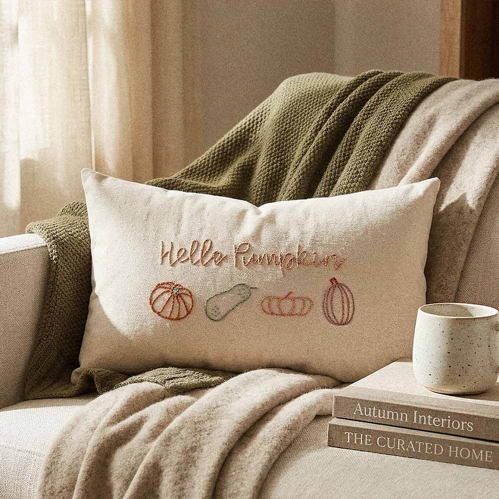 Hello Pumpkin Embroidered Lumbar Pillow | Hand-Stitched Fall Decor | Natural Cotton 4 Fall lumbar pillow in natural cotton styled on neutral linen bed with pampas grass and candle