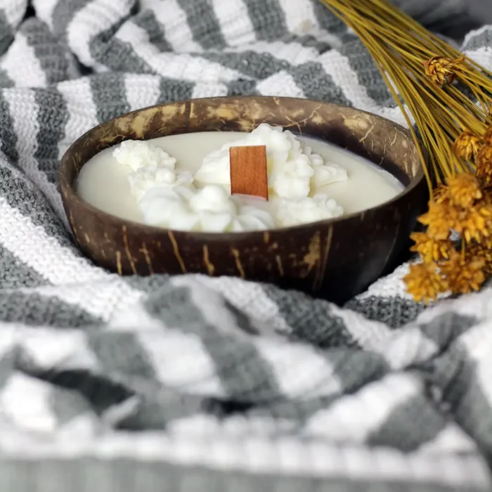 wood wick dough bowl candle Candle Dough Bowl - Soy candle in a natural coconut bowl, featuring a wooden wick and decorative, flower-shaped wax accents, set against a gray and white knitted background. wood wick dough bowl candle