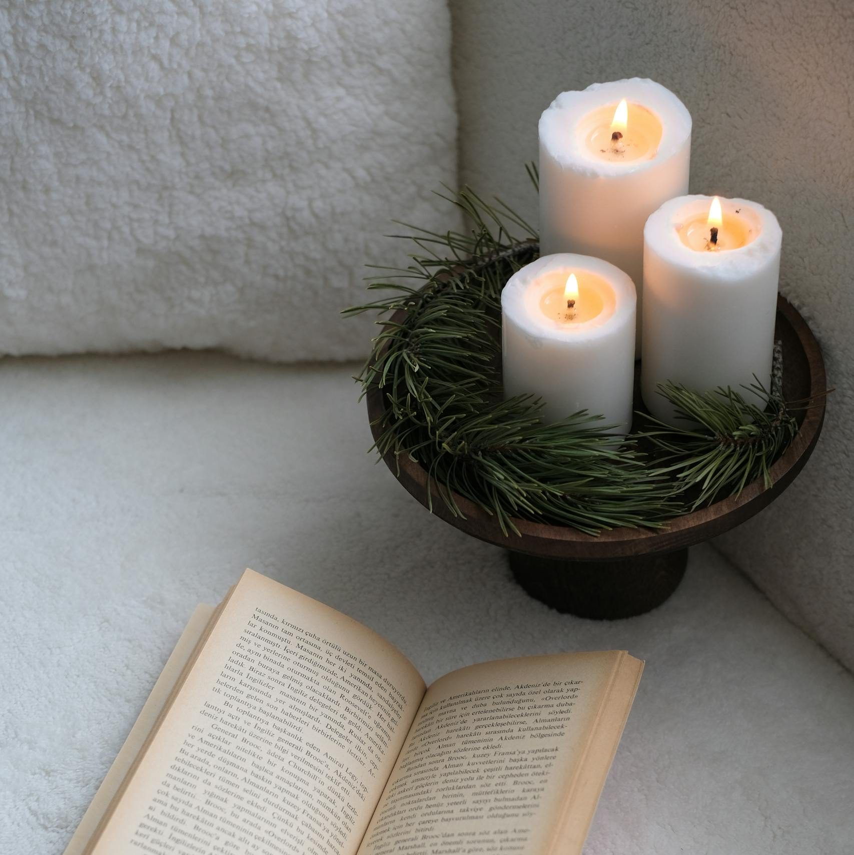 A book and clean burning candles on a white couch