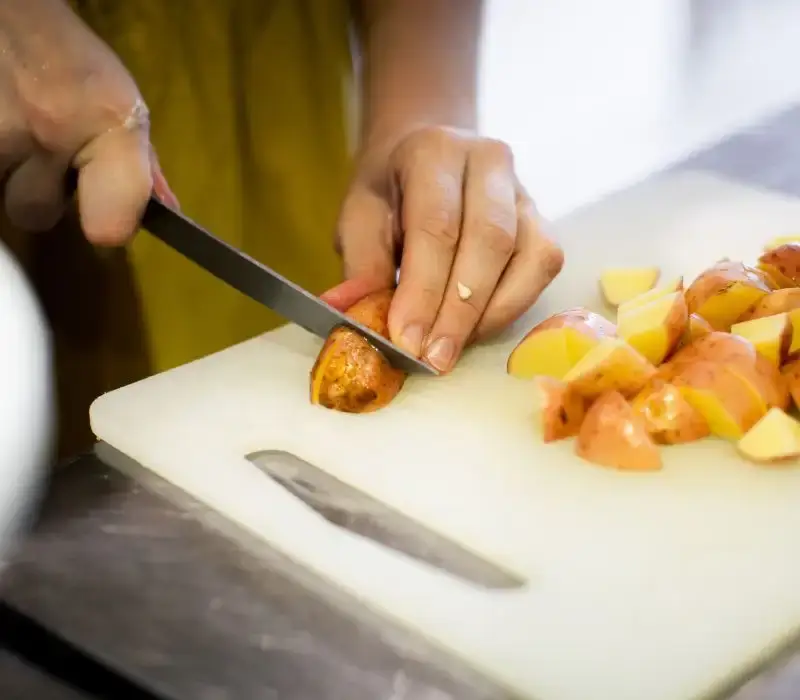 Non Toxic Cutting Boards: Top Picks for a Healthy Kitchen in 2024 4 hand cutting potatoes on plastic cutting board