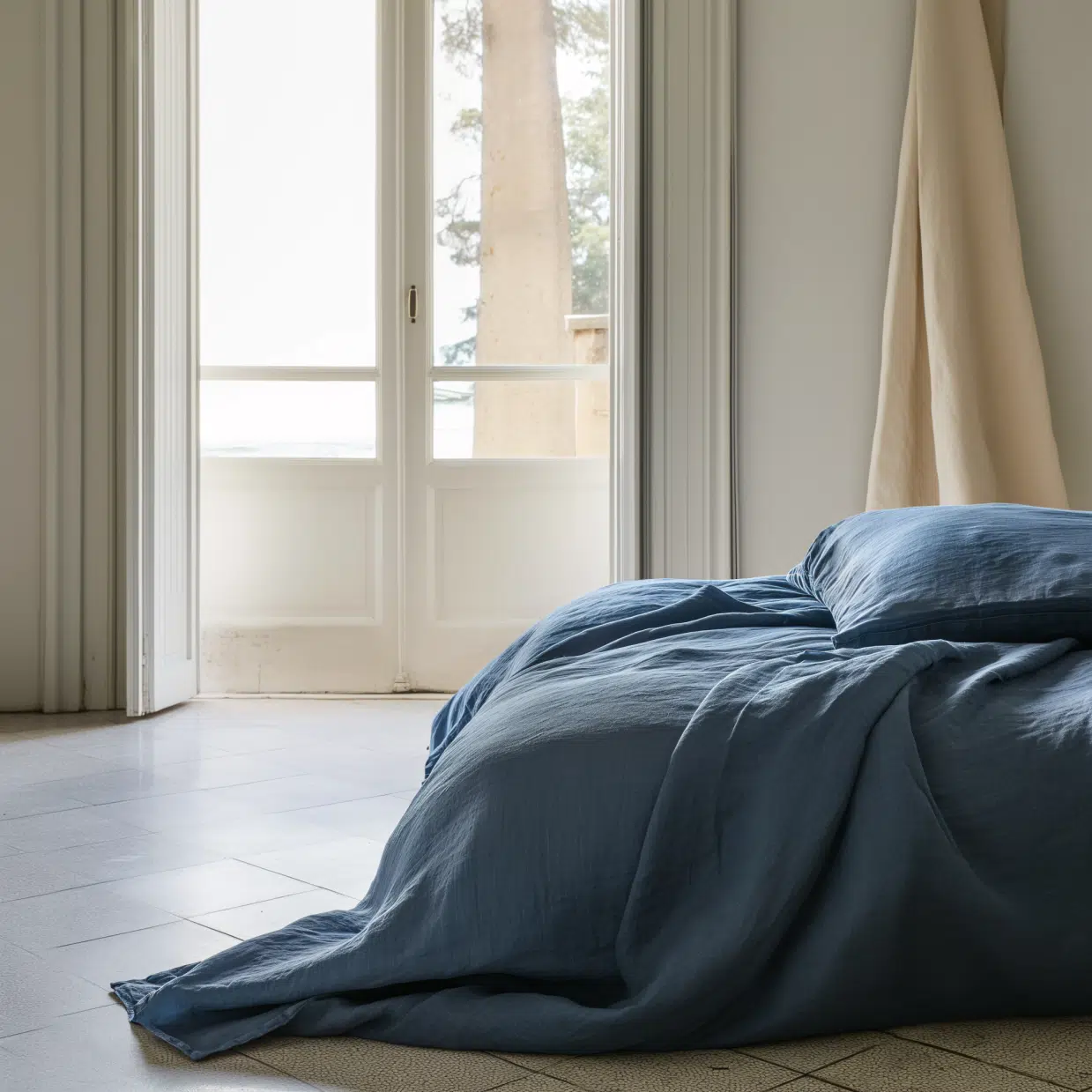 a bed covered in a blue duvet cover in a brightly lit bedroom