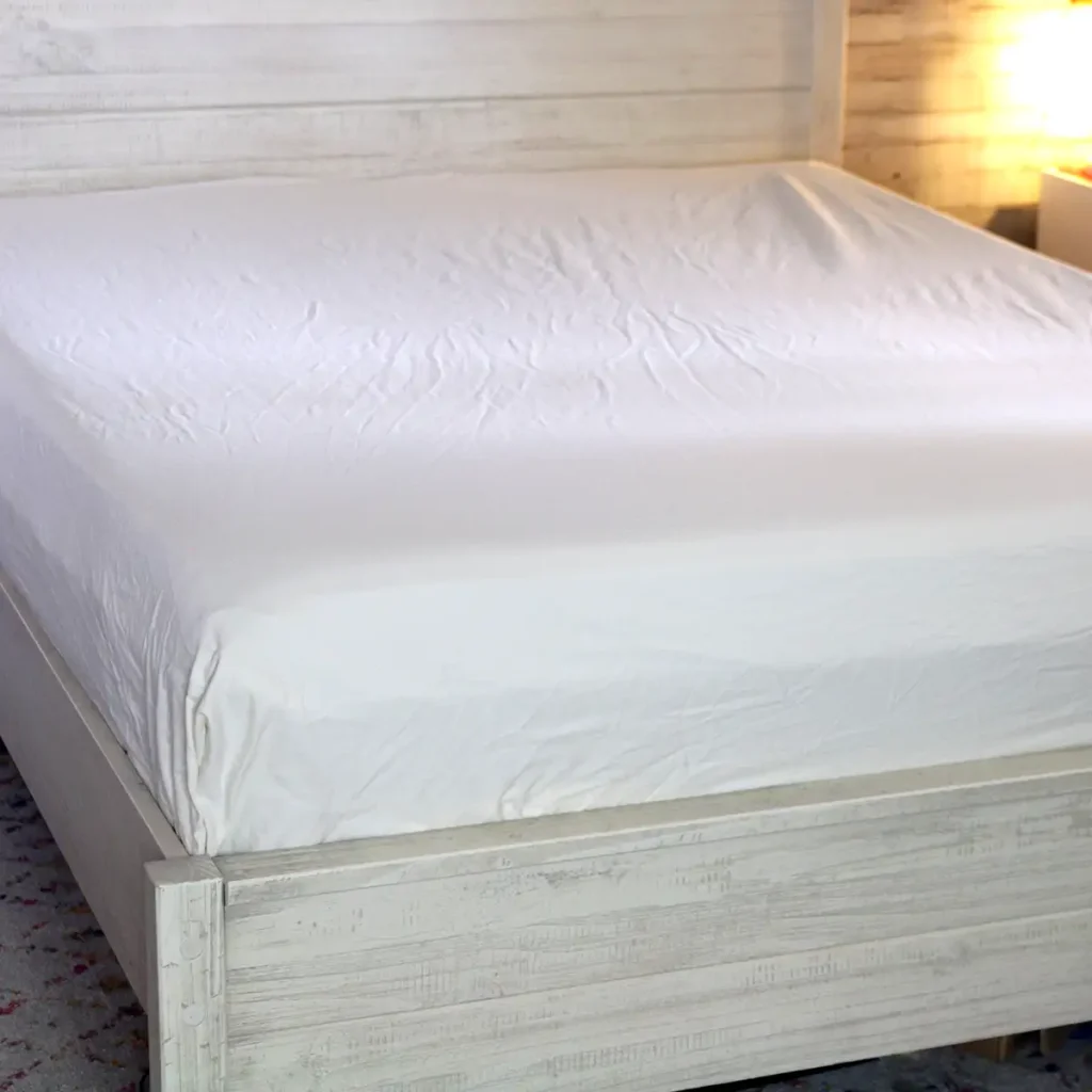 A bed layered with fitted sheet and flat sheet demonstrating how to layer a bed the right way