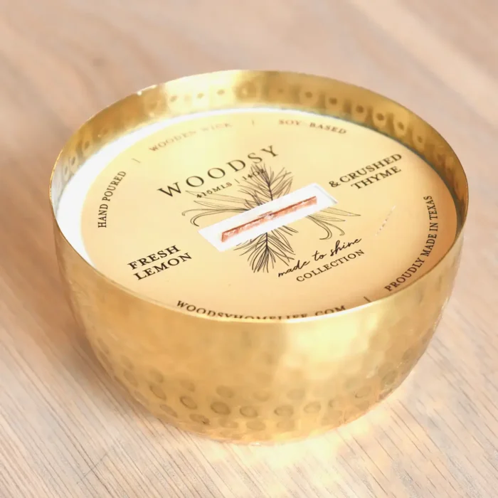 Solid Brass 14oz Pure Soy Candle Solid Brass 14oz Pure Soy Candle with Label: A solid brass soy candle with a wooden wick, showing the label with the text "WOODSY Fresh Lemon & Crushed Thyme" and other details.