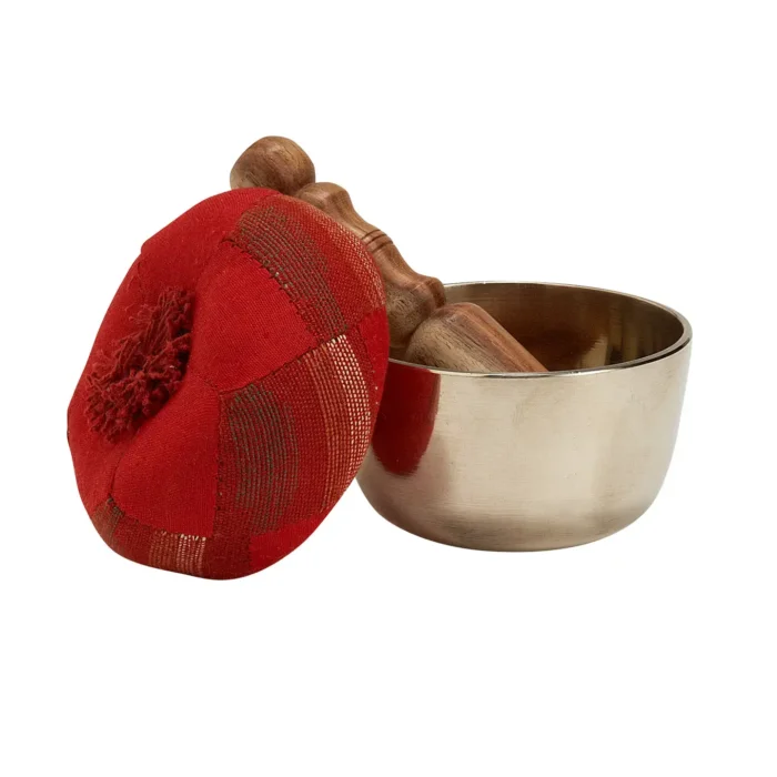 Tibetan singing bowls Close-up of the Tibetan Singing Bowl Set featuring a brass bowl, wooden mallet, and red cushion.