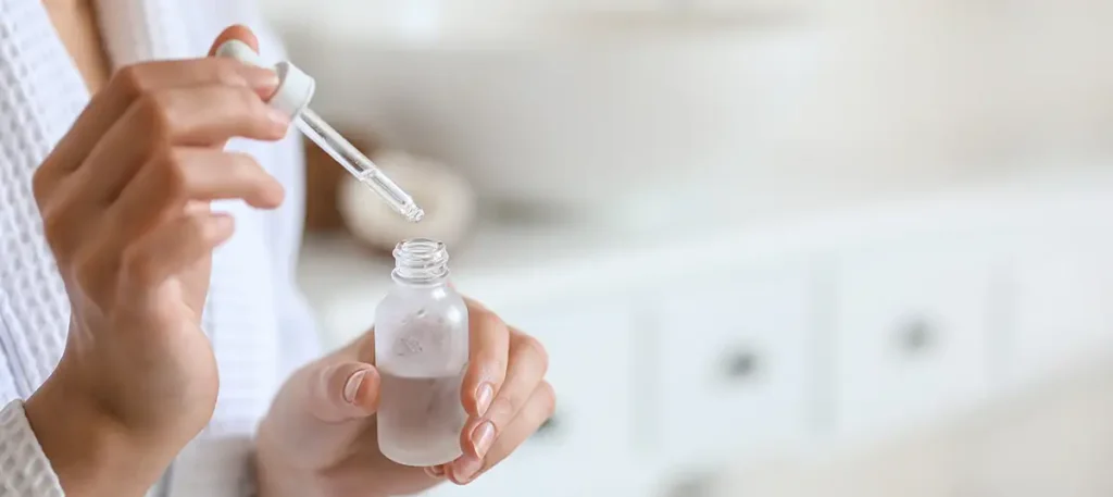 The Benefits of Using Essential Oils in Your Laundry 4 Person holding a dropper bottle. Best essential oils to use in your laundry.