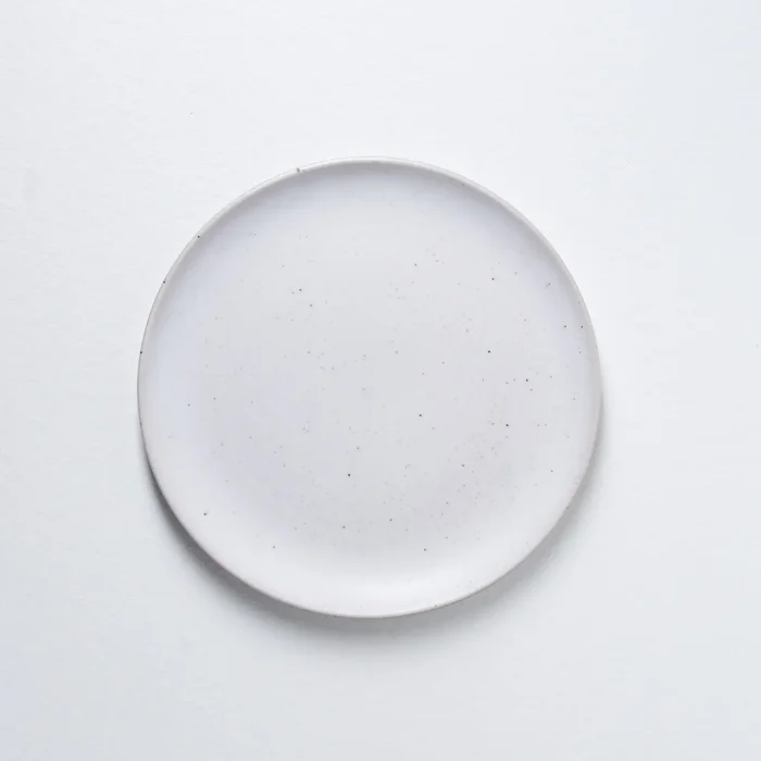 A single white Portuguese dinner plate viewed from above, displaying its minimalist and clean design.
