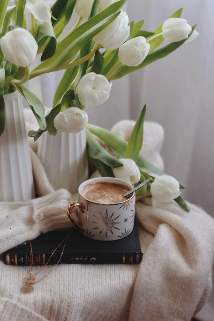 How to Achieve Modern Farmhouse Decor - From Pinterest to Reality 2 From above of ceramic cup of hot chocolate with spoon placed on book on warm sweater near vases with delicate white tulips. modern farmhouse decor