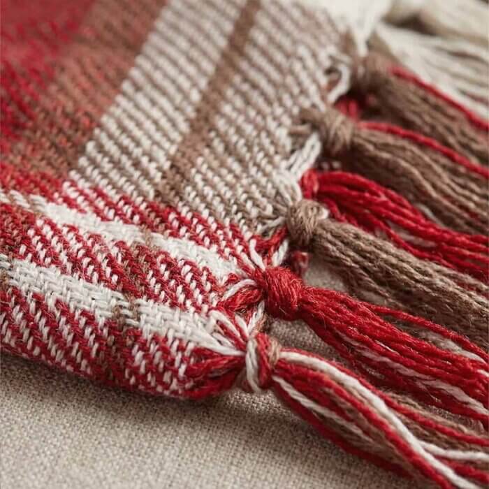 Red and White Plaid Throw Blanket with Fringe Extreme close-up of a red and white plaid throw blanket showing the thick, breathable cotton weave. The focus is on the twisted fringe tassels, highlighting the handmade artisanal quality of the textile."