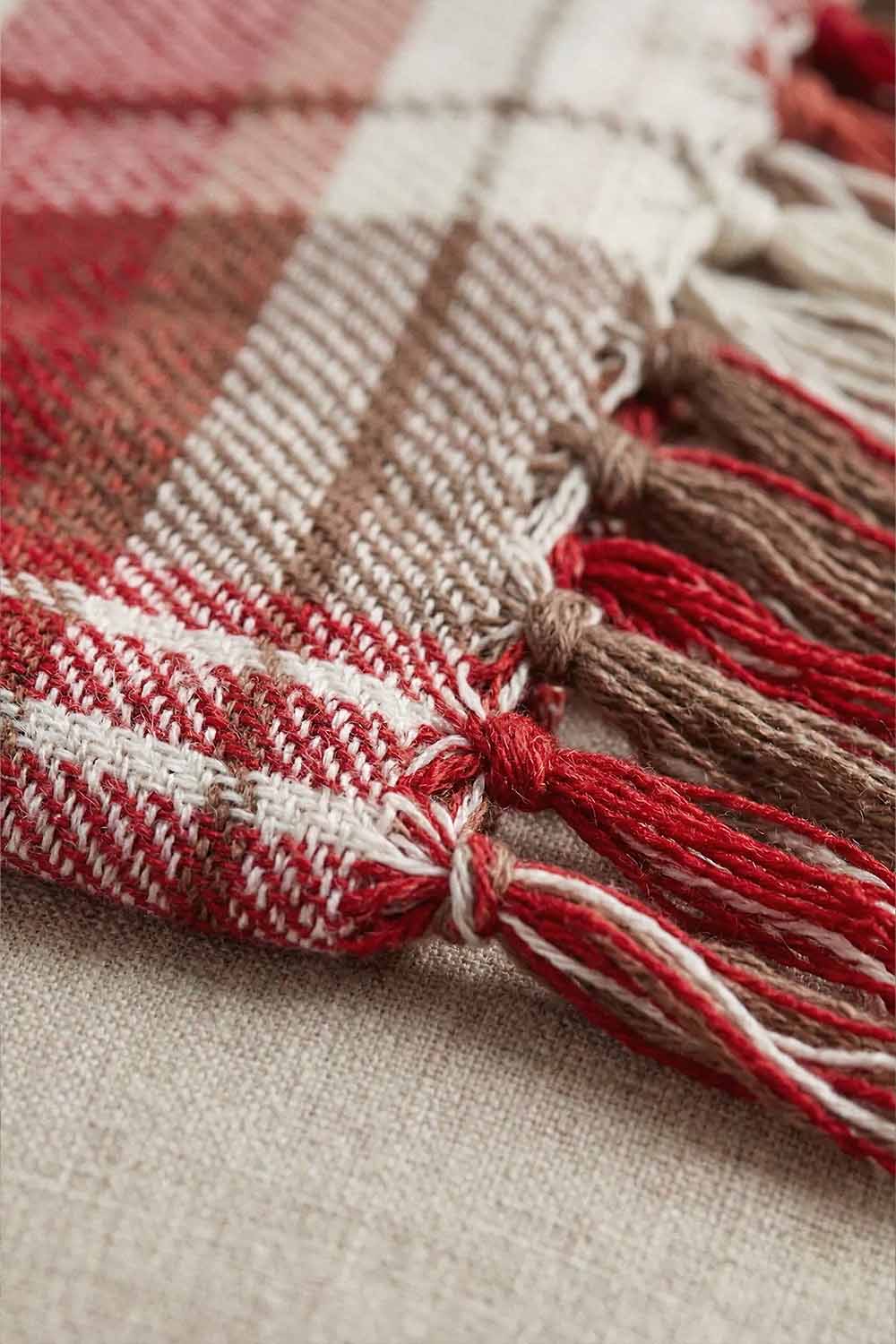 Red and White Plaid Throw Blanket with Fringe 2 Extreme close-up of a red and white plaid throw blanket showing the thick, breathable cotton weave. The focus is on the twisted fringe tassels, highlighting the handmade artisanal quality of the textile."