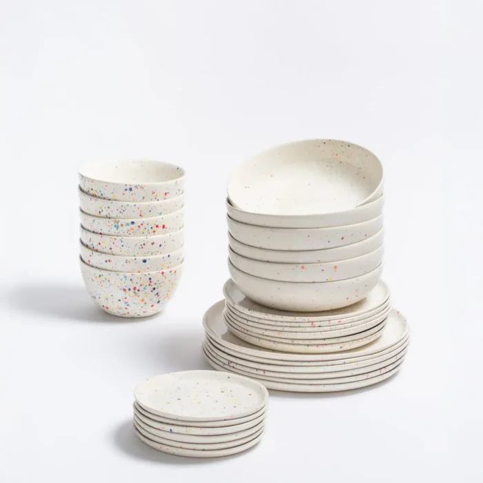 White Ceramic Dinnerware. A stack of 16 white ceramic dishes including dinner plates, salad plates, pasta plates, and bread plates. Each piece is decorated with bright, colorful confetti speckles like a celebration