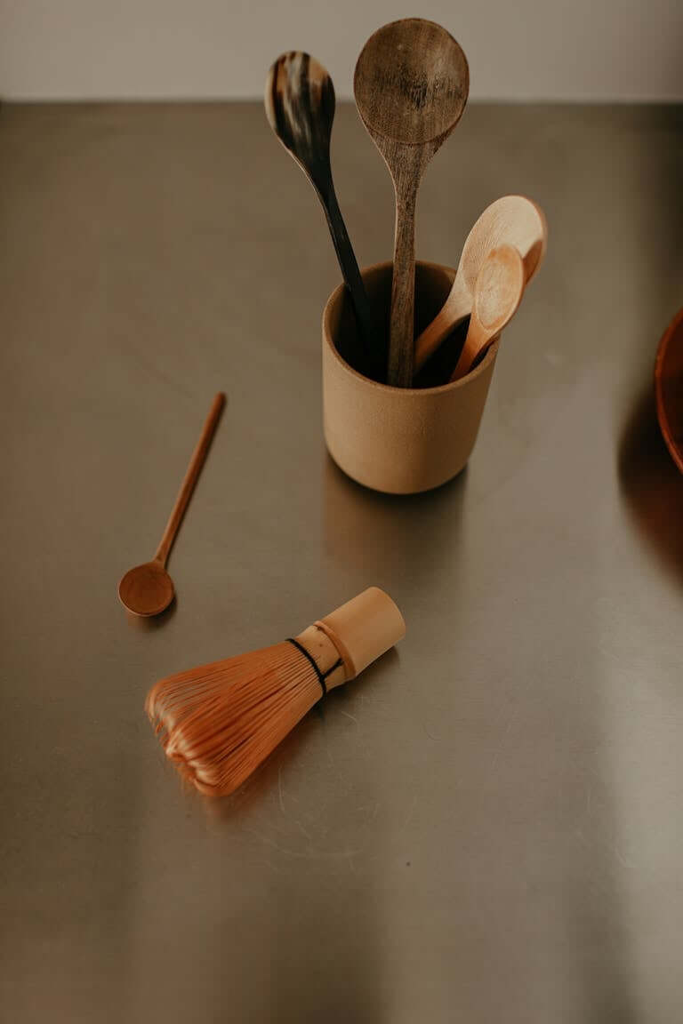 15 Non Toxic Kitchen Essentials for a Safer, Eco-Friendly Kitchen 4 Minimalist photo featuring wooden spoons and whisk on a kitchen counter, perfect for culinary themes.