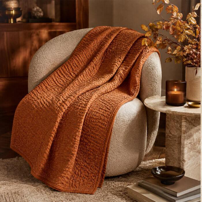Terracotta Kantha throw blanket draped over a neutral living room couch